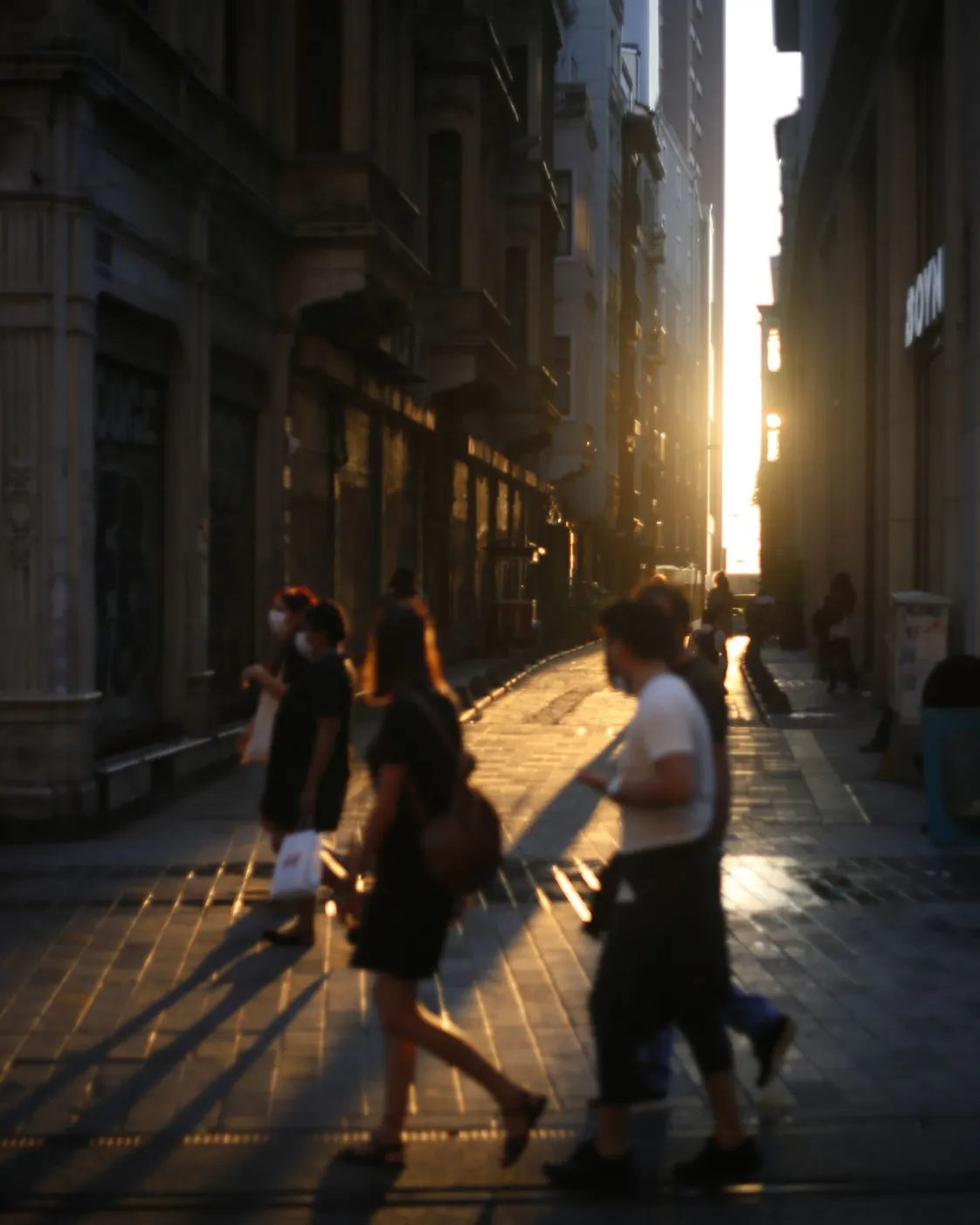 Pedestrians walking down a city street at dusk
